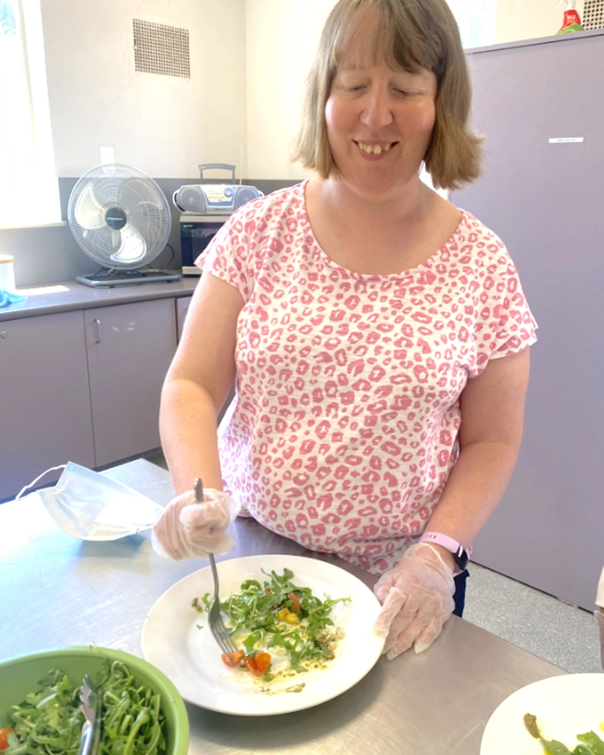 A woman eats salad from a plate at NDIS registered disability service Distinctive Options