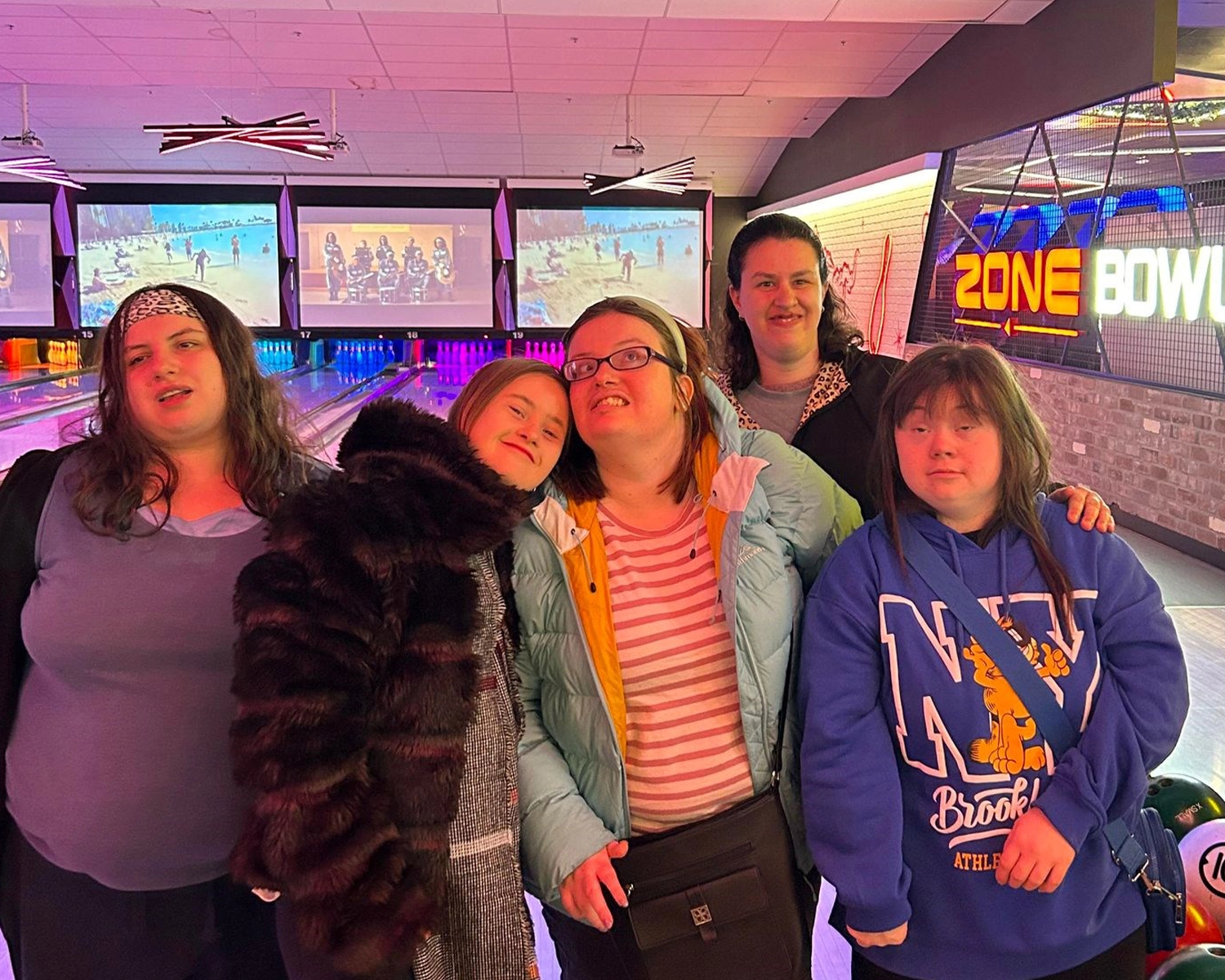 A group of young women smile while standing inisde a ten pin bowling alley at Watergardens with Distinctive Options