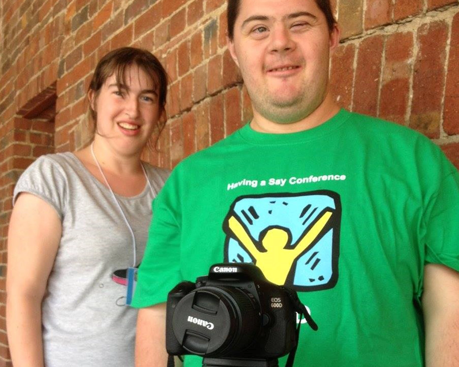 A man and a woman stand next to a camera on tripod atNDIS registered disability service Distinctive Options