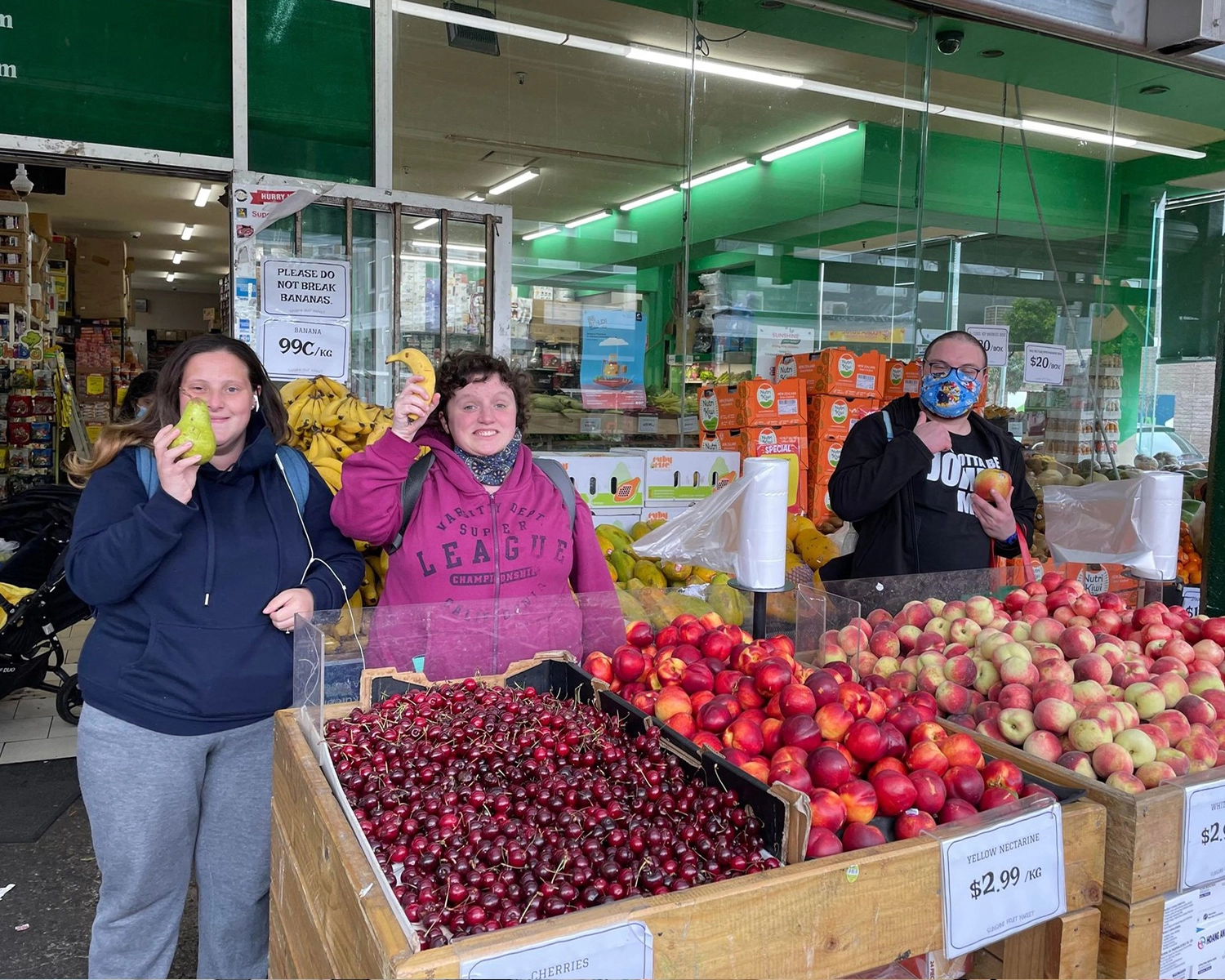 3 people stand outside a fruit and vegetable store at NDIS registered disability support Distinctive Options