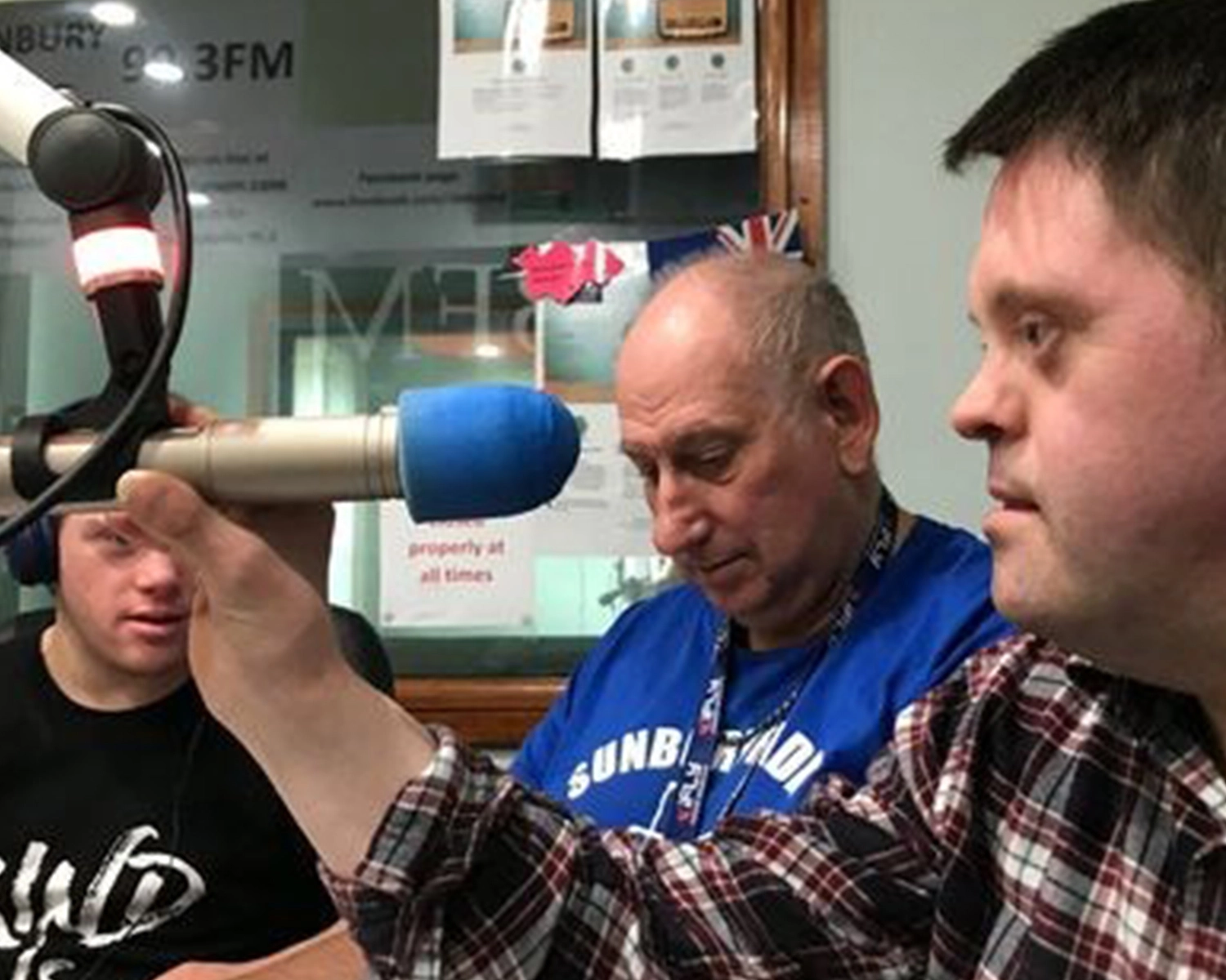 Three people sit inside a radio studio at NDIS registered disability service Distinctive Options