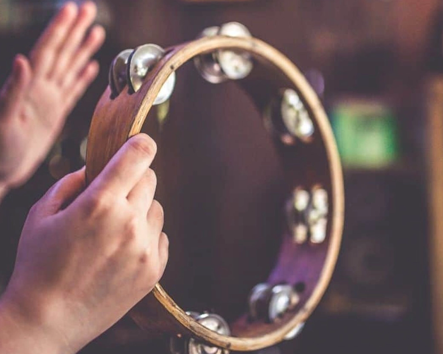 A pair of hands play a tambourine at NDIS registered disability service Distinctive Options