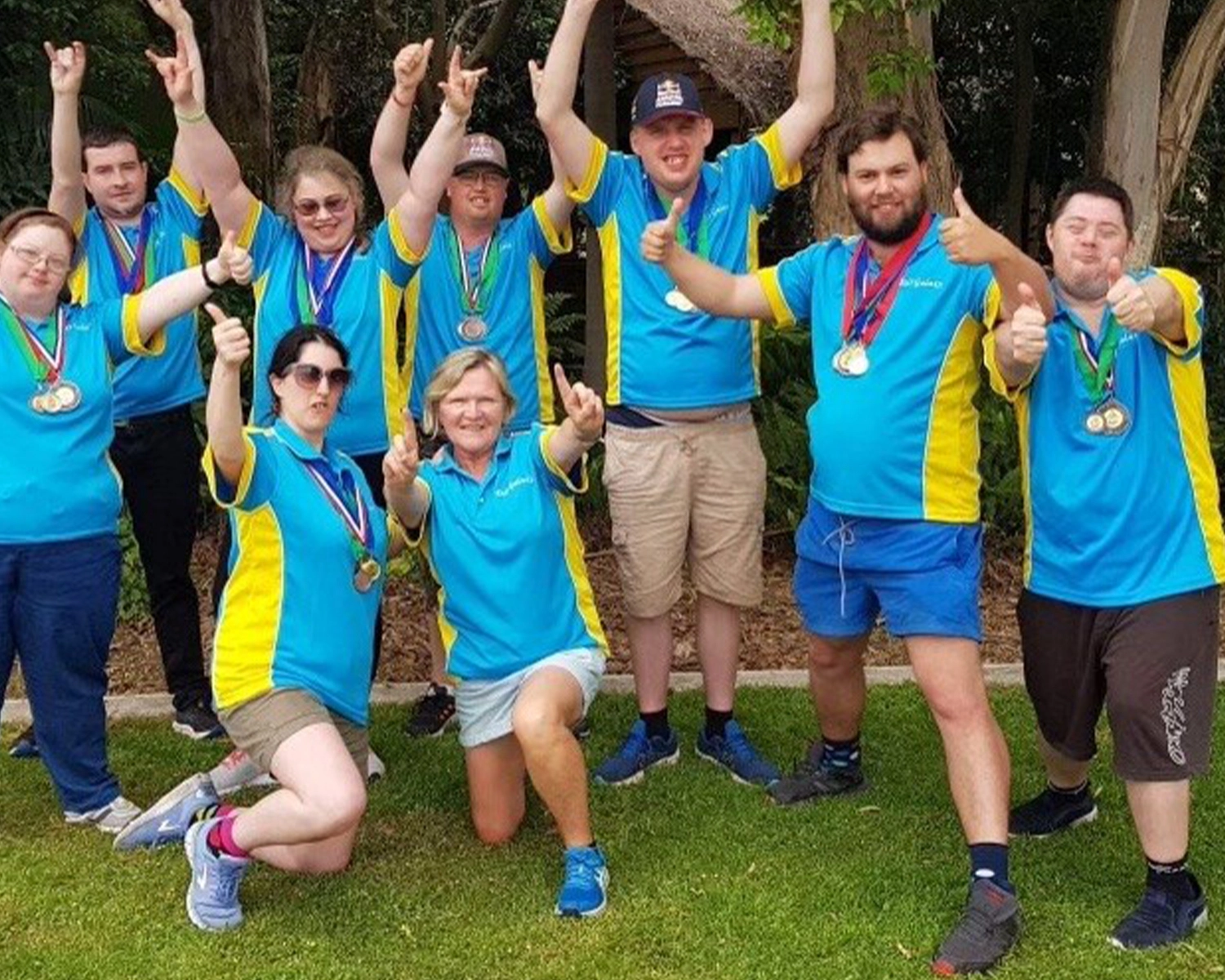 A group of people wearing team colours smile at NDIS registered disability service Distinctive Options